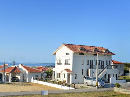 a white house with a car parked in front of it at Oceanview Yui in Ishigaki Island