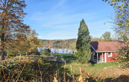 a house and a tree next to a lake at Two-Bedroom Holiday Home In Lammhult in Lammhult