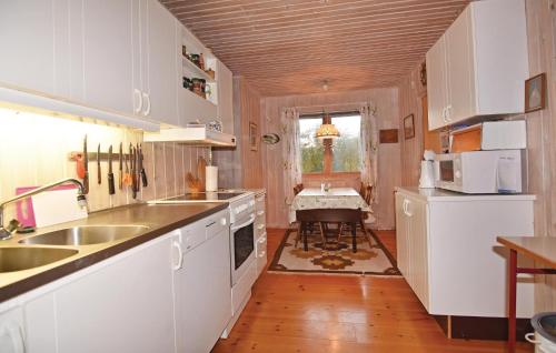ストレムスタードにある2 Bedroom Beautiful Home In Strmstadの白いキャビネット、シンク、テーブル付きのキッチンが備わります。