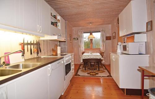 a kitchen with white cabinets and a sink and a table at Nice Home In Strmstad With 2 Bedrooms in Strömstad