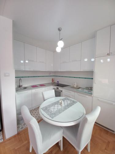 a white kitchen with a white table and white chairs at APARTMAN PETRA Lux in Plužine