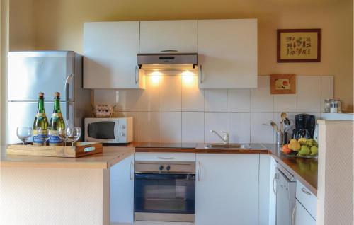 - une cuisine avec des placards blancs et des bouteilles de vin dans l'établissement Cozy Home In Trie-Château With Wifi, à Trie-Château