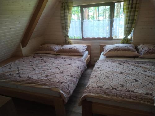 2 Einzelbetten in einem Zimmer mit Fenster in der Unterkunft Chata Sosna in Spišská Nová Ves
