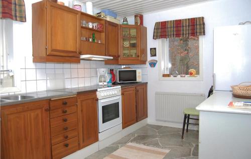 a kitchen with wooden cabinets and a stove top oven at 2 Bedroom Beautiful Home In Örkelljunga in Drakabygget
