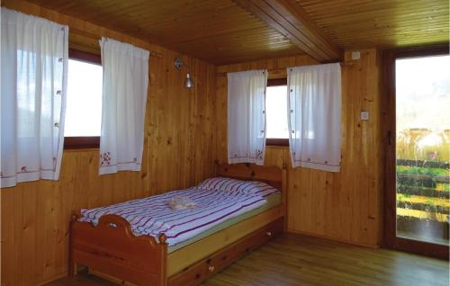 a small bed in a wooden room with windows at 2 Bedroom Stunning Home In Luce in Luče