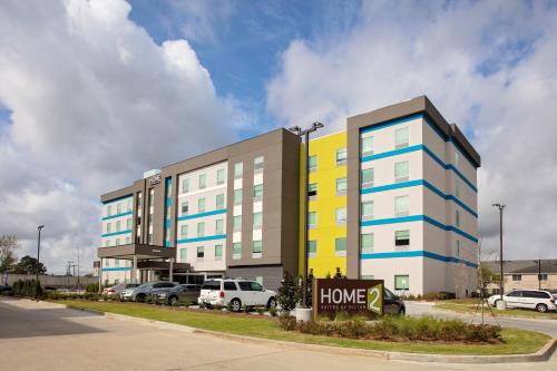 a large apartment building with cars parked in a parking lot at Home2 Suites By Hilton Baton Rouge Citiplace in Baton Rouge