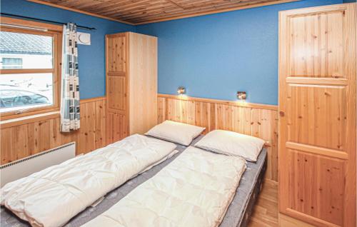 VestvikにあるNice Home In Auklandshamn With 4 Bedrooms, Sauna And Wifiの青い壁の客室の大型ベッド1台分です。