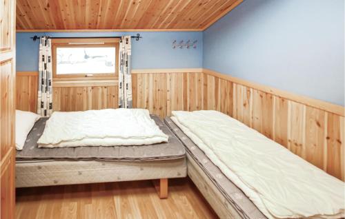 two beds in a room with wooden walls and a window at Amazing Home In Auklandshamn With Sauna in Vestvik