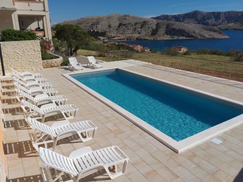 a swimming pool with white chairs next to a swimming pool at Apartment Ante K A1 in Metajna