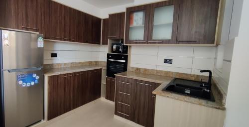 a kitchen with wooden cabinets and a stainless steel refrigerator at English Point Residence Beach Apartments Mombasa in Mombasa