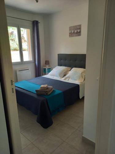 a bedroom with a bed with a blue comforter and a window at hébergement figari in Figari