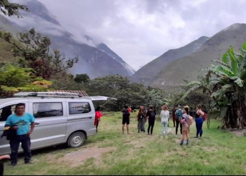 a group of people walking in a field next to a van at Eco Hacienda Roman in Machu Picchu
