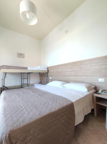 een slaapkamer met een groot bed en een stapelbed bij Hotel Galassia in Rimini