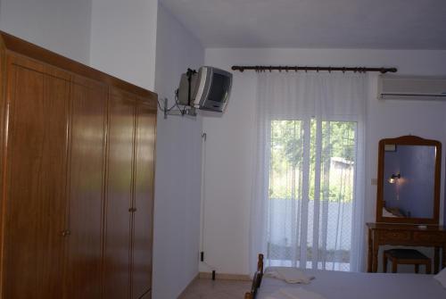 ein Schlafzimmer mit einem TV an einer Wand neben einem Fenster in der Unterkunft Andrianna Apartments in Ammoudia