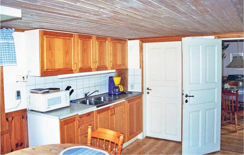 - une cuisine avec des placards en bois et un four micro-ondes blanc dans l'établissement Stunning Home In Kristdala With Kitchen, à Malghult