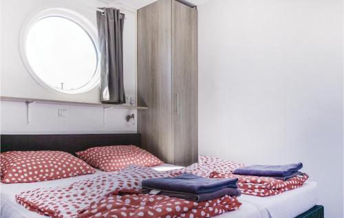 uma cama com almofadas vermelhas e brancas e uma janela em Aquacabin em Leimuiden
