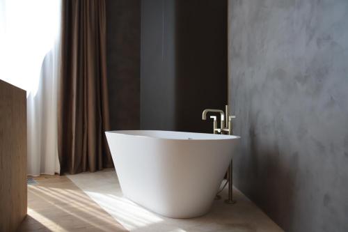 a white bath tub in a bathroom with a window at The Veil Hotel in Astana