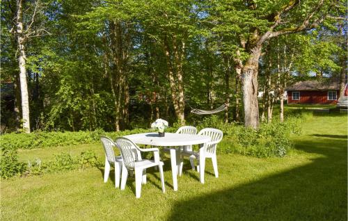 a white table and chairs in a yard with trees at Awesome Apartment In Rönneshytta in Rönneshytta
