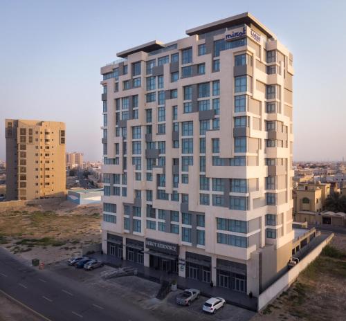 a tall white building with cars parked in front of it at فندق ميروت-Mirot Hotel in Al Khobar