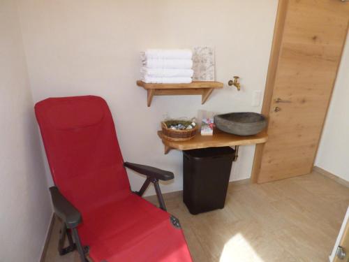 a red chair in a room with a table and towels at Alpenchalet Breitspitz in Partenen