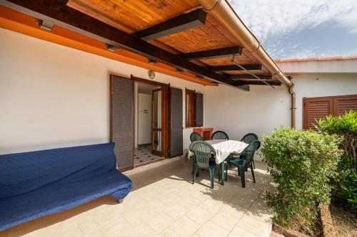 a patio with a table and chairs and a bed at Villetta Teresa in Costa Rei