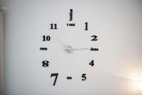 a white clock with black numbers on a wall at Villetta Teresa in Costa Rei