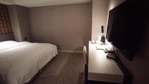 a bedroom with a bed and a flat screen tv at City Suites - Taoyuan Gateway in Dayuan