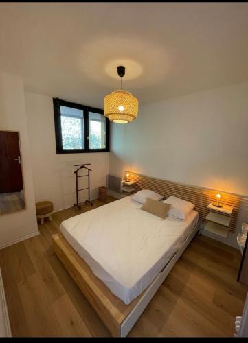 une chambre avec un grand lit et un lustre dans l'établissement Logement charmant au coeur de la station, à Besse-et-Saint-Anastaise