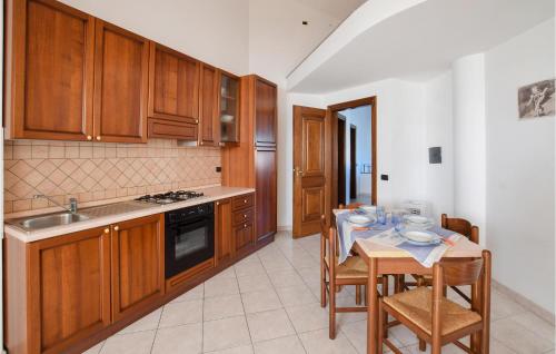 a kitchen with wooden cabinets and a table with chairs at Gorgeous Apartment In Ricadi With Wifi in Ricadi
