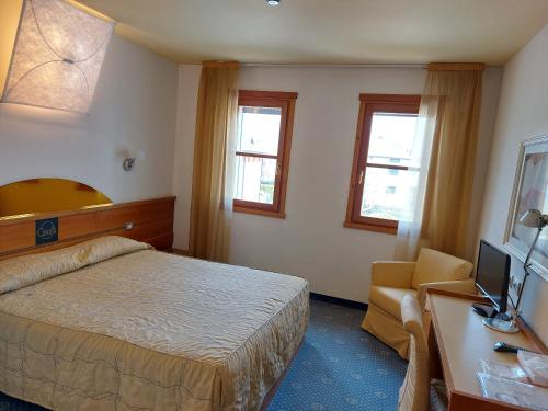 1 dormitorio con 1 cama y escritorio con TV en Hotel Ristorante La Casona, en Feltre