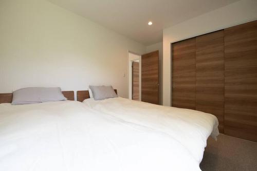 a bedroom with a large white bed and wooden cabinets at Yuki no Taki 2 in Niseko