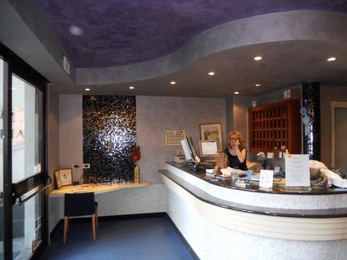 a woman sitting at a bar in a restaurant at Hotel Astoria in Fidenza