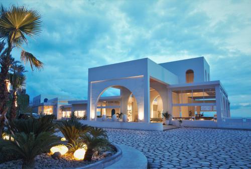 a white building with a palm tree in front of it at Royal Avila Boutique Resort in Senggigi 