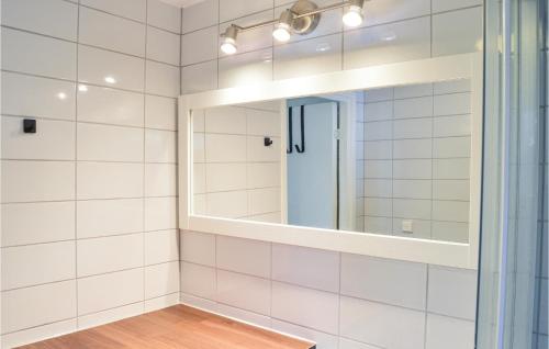 a bathroom with white tiled walls and a mirror at Two-Bedroom Holiday Home In Ingaro in Grönskan