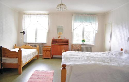 a bedroom with two beds and two windows at Awesome Home In Svrdsj With 6 Bedrooms, Sauna And Wifi in Vintjärn