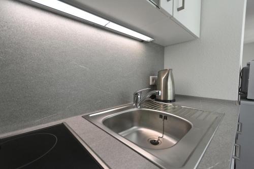 um lavatório de aço inoxidável numa cozinha com luz em Aparthotel Stoll em Bad Soden am Taunus