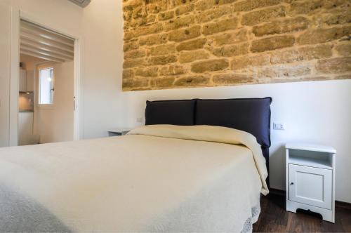 a bedroom with a bed and a brick wall at Loft In The Old Town in Alghero