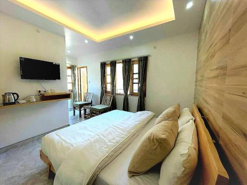 a bedroom with a large bed and a flat screen tv at The Wild Yak in Mandi