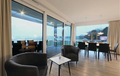 a dining room with a table and chairs and large windows at Priwallpromenade 1, Whg 3 in Travemünde