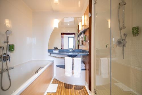 a bathroom with a tub and a sink and a shower at B&B HOTEL Calais Terminal Cité Europe 4 étoiles in Coquelles