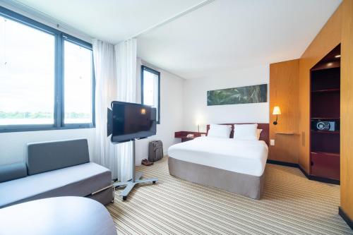 コケルにあるB&B HOTEL Calais Terminal Cité Europe 4 étoilesのベッド1台、薄型テレビが備わるホテルルームです。
