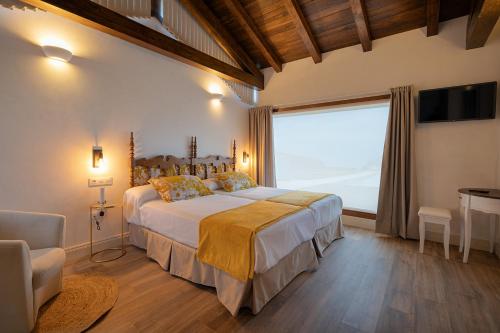 a bedroom with a large bed and a large window at Hotel Rural La Sobreisla in Puerto de Vega