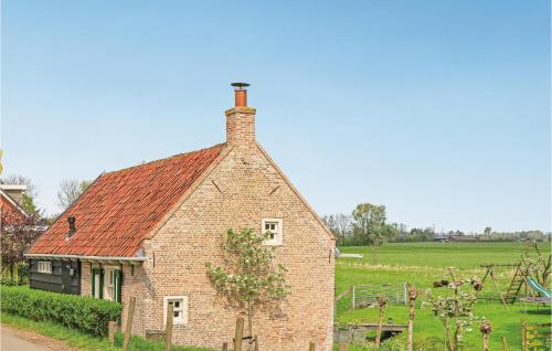 a brick house with a red roof in a field at Het Kleinste Huisje in Maasdam
