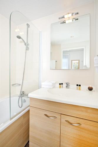 une salle de bain avec un lavabo blanc et une douche dans l'établissement Residhome Clermont Ferrand Gergovia, à Clermont-Ferrand