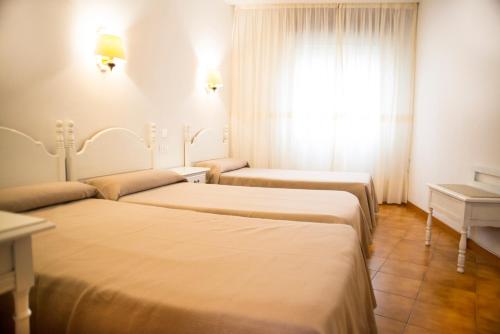 a hotel room with two beds and a window at Hotel Cachalote in Portonovo