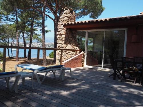 a deck with chairs and a stone fireplace at Villa PINEDE in Porto-Vecchio