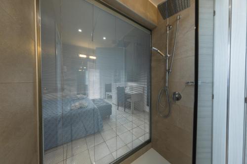 y baño con ducha y puerta de cristal. en Hotel Baia Del Capitano, en Cefalú
