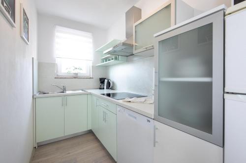 a kitchen with white cabinets and a stainless steel refrigerator at Apartment Kosic n1 beautiful & cosy in Krk