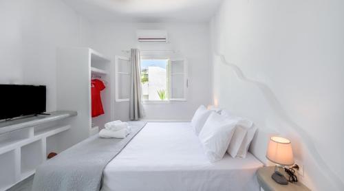 a white bedroom with a bed and a television at Pente Elies Milos in Pollonia