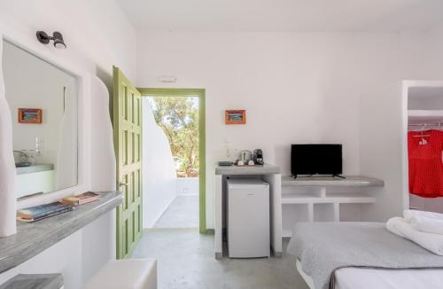 a room with a bed and a desk with a television at Pente Elies Milos in Pollonia